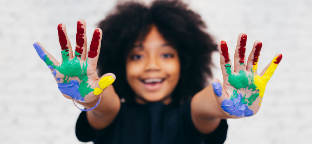 photo of a child with multicoloured paint on their hands